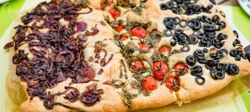 Focaccia mit Zwiebeln, Tomaten und Oliven.